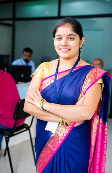 vertical shot Happy confident bank employee standing with arms crossed by looking camera at office - concept of successful career, leadership and financial service or support.