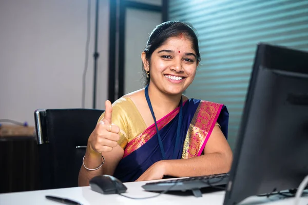 Happy smiling corporate or banking employee showing thumbs up by looking camera at bank - concept of successful, confident and banking service