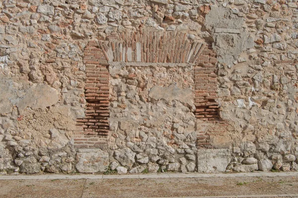 condemned and bricked up door in a brick and stone wall