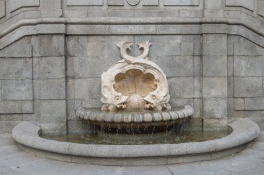 Madrid 'de bir sokakta iki balık ve bir deniz kabuğu bulunan tarihi taş çeşme. İspanya