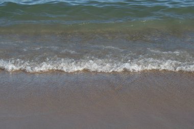 background with a wave of white foam reaching a beach in Barcelona. Spain