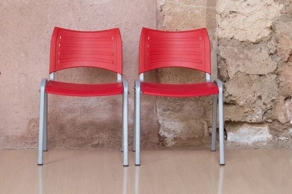 Duas Cadeiras Plástico Vermelho Isolado Com Fundo Pedra Atrás — Fotografia de Stock