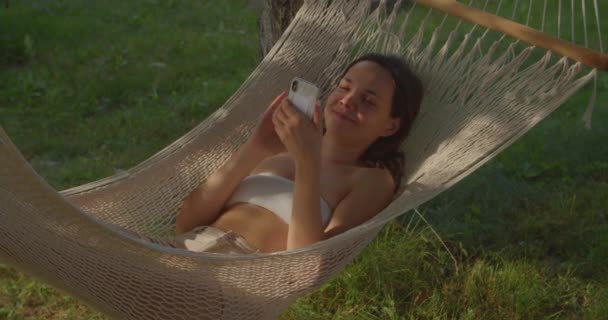 少女躺在吊床上浏览社交网站 — 图库视频影像