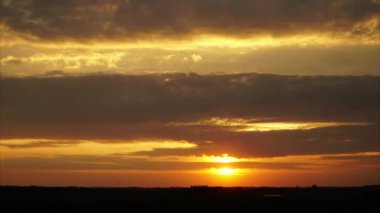 Günbatımının hızlandırılmış görüntüleri, gecenin geç saatlerinde hızlı yüzen bulutlar ve alacakaranlık saatleri. Dramatik gri bulutlarla kaplı güzel turuncu güneş ışığı.