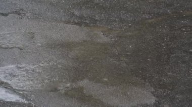 Yağmur damlaları asfalttaki su birikintilerine düşer. Yağmur yağıyor. Yağmurun soyut bir görüntüsü. Yağmurlu, kasvetli hava.
