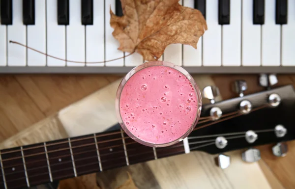 Fresh cold raspberry smoothie, yellow leaf, guitar and piano