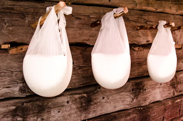 Traditional sheep cheese hanging in white cheese cloth drying. — Stock Photo, Image