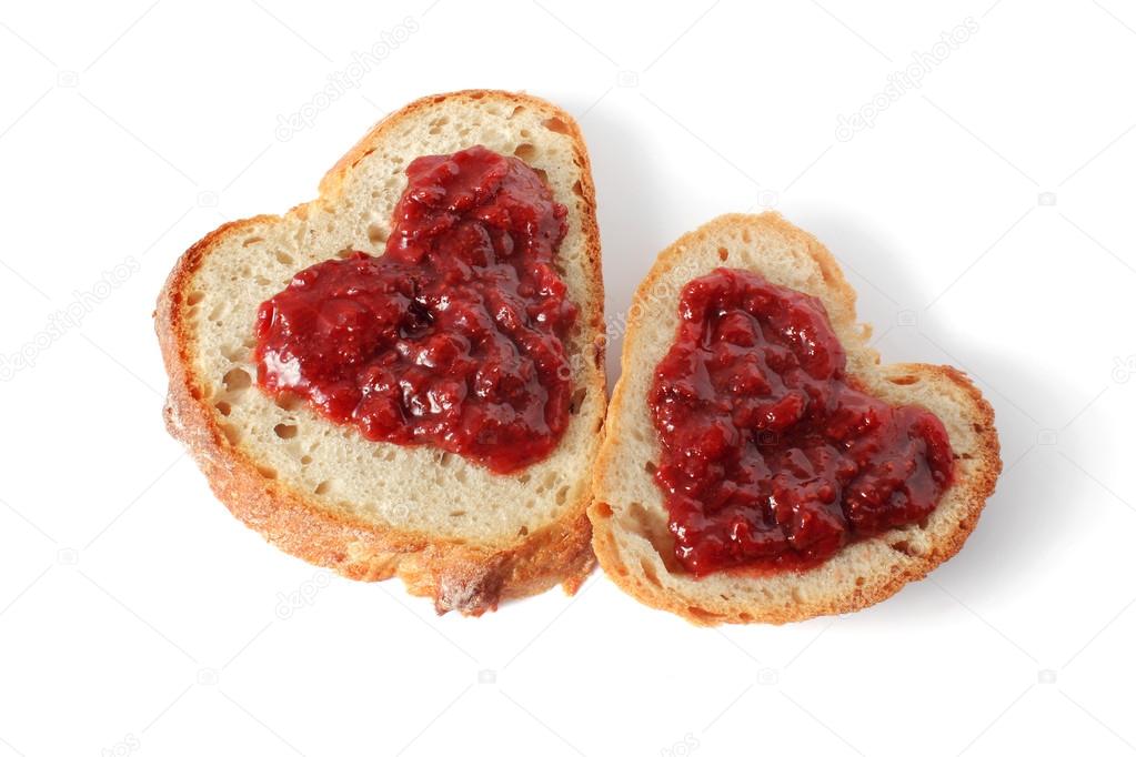 Two slices of heart shaped bread with jam isolated on white background
