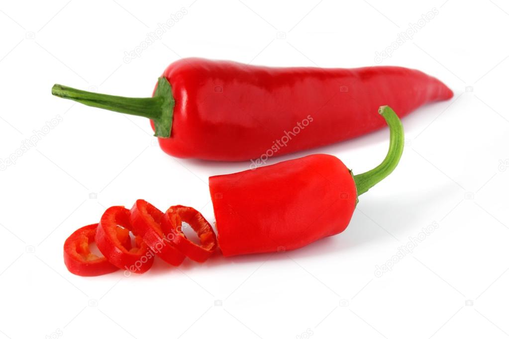 Sliced red chili pepper and one whole on white