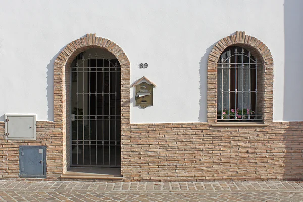 Puerta y ventana con barras en la pared blanca — Foto de Stock
