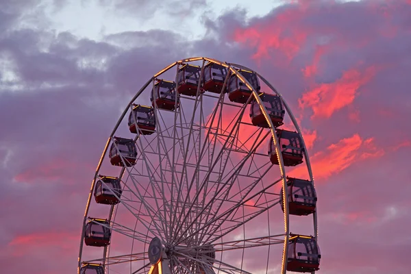 Roda gigante no parque de diversões e nuvens vermelhas no fundo — Fotografia de Stock