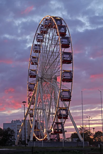 Roda gigante no parque de diversões contra as nuvens vermelhas — Fotografia de Stock