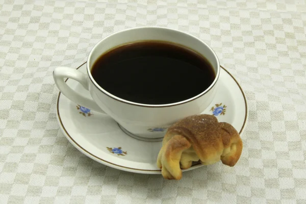 Kaffee aus Porzellan mit kleinem Croissant auf Tischdecke — Stockfoto