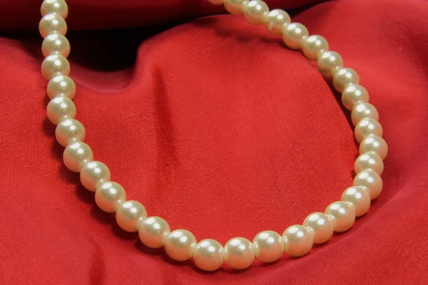 Collana di perle su tessuto rosso — Foto Stock