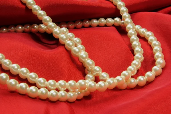 Pearls on red fabric — Stock Photo, Image