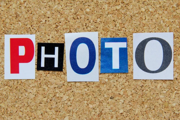 Word photo cut from newspaper on cork background — Stock Photo, Image