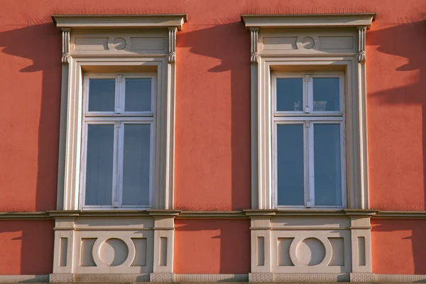 Dos ventanas con decoración ornamental en la pared roja Cracovia, Polonia — Foto de Stock