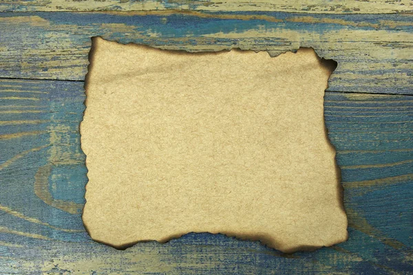 Burnt paper on blue old wood background — Stock Photo, Image