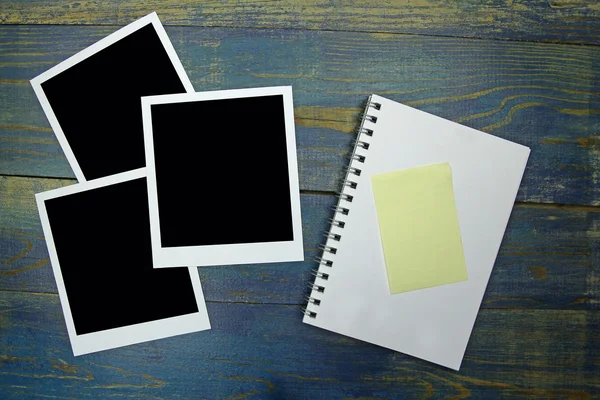Prázdné notebook s nálepkou a foto rámeček na dřevěné pozadí — Stock fotografie