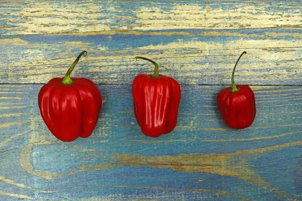 Three chili peppers on old wood background — Stock Photo, Image
