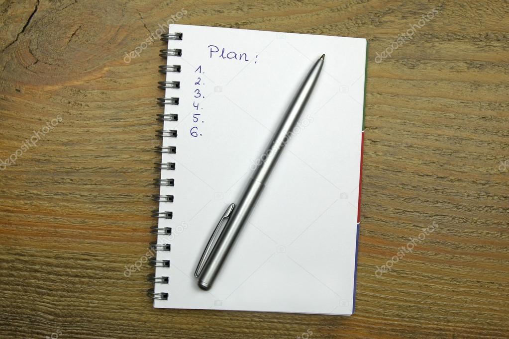 notebook with an action plan on wooden desk