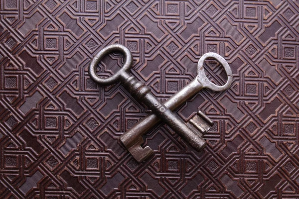 Duas chaves enferrujadas cruzadas no fundo padrão de couro — Fotografia de Stock