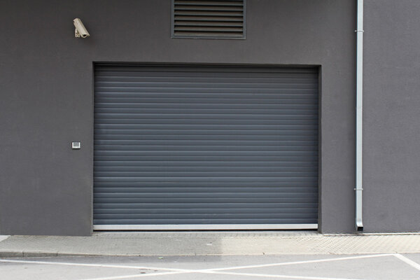 Fragment of wall with roller shutter door, camera and intercom
