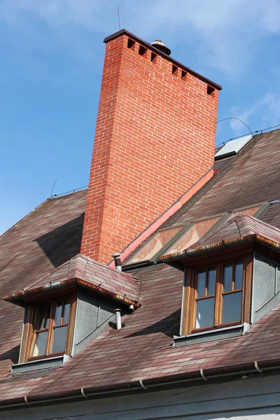 Roof with brick chimney and two vertical windows — Stock Photo, Image