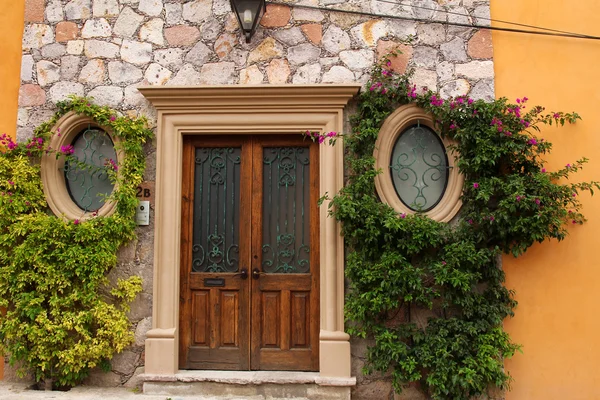 Porta de entrada com duas janelas redondas na parede laranja com sto — Fotografia de Stock