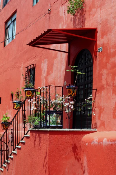 Красное здание с лестницами и цветочными горшками — стоковое фото
