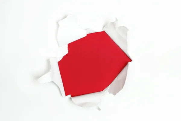 Red hole in white paper with ragged edges — Stock Photo, Image