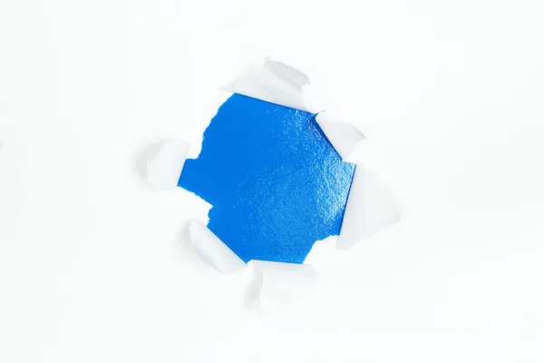 Blue hole in white paper with ragged edges — Stock Photo, Image