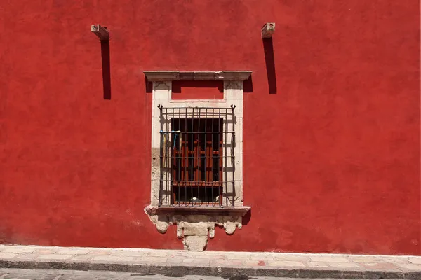 Window with bars in red wall — Stock Photo, Image