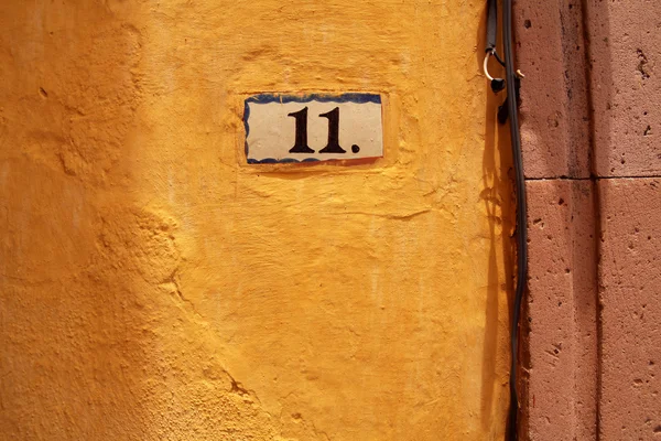 Number eleven on yellow wall, house address plate number — Stock Photo, Image