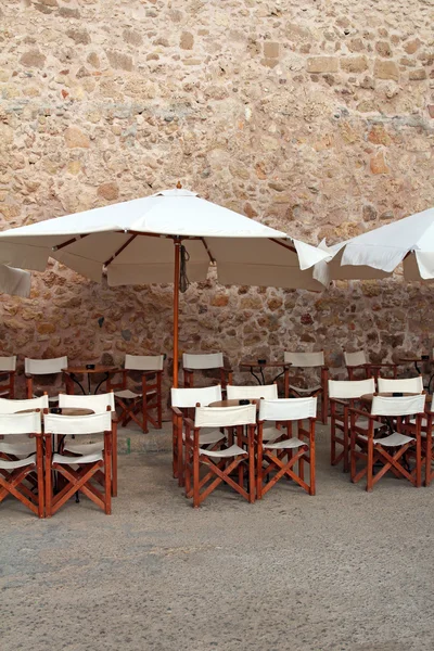 Café de rua com cadeiras de madeira e guarda-chuvas brancos — Fotografia de Stock