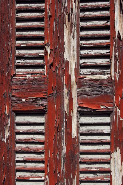 Old wooden shutter with red peeling paint — Stock Photo, Image