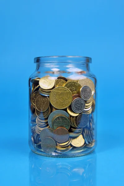 Un frasco abierto con monedas sobre fondo azul — Foto de Stock