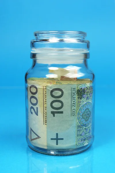 Jar met Poolse zloty bankbiljetten op blauwe achtergrond — Stockfoto