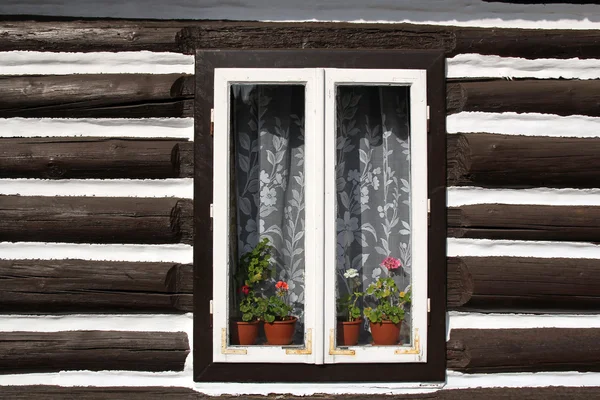 Janela com flores na parede da velha casa de madeira — Fotografia de Stock