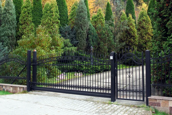 Чорні сучасні ворота і зелений сад — стокове фото