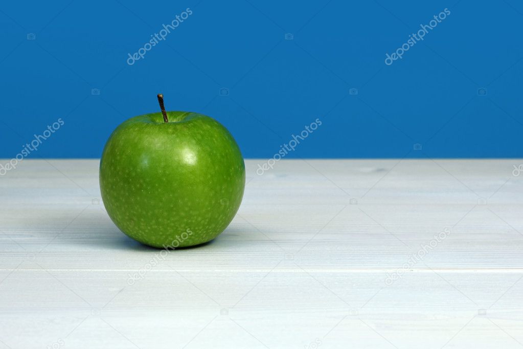 Green apple on white wooden surface