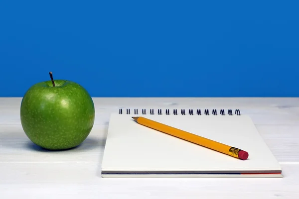 Manzana verde y cuaderno con lápiz sobre escritorio de madera blanca —  Fotos de Stock