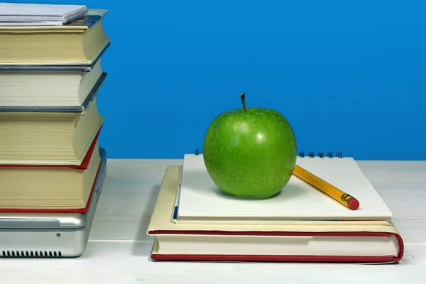 Högen av böcker, laptop, grönt äpple och penna — Stockfoto