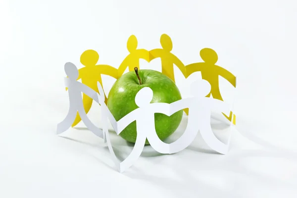 Circle of paper people around the green apple — Stock Photo, Image