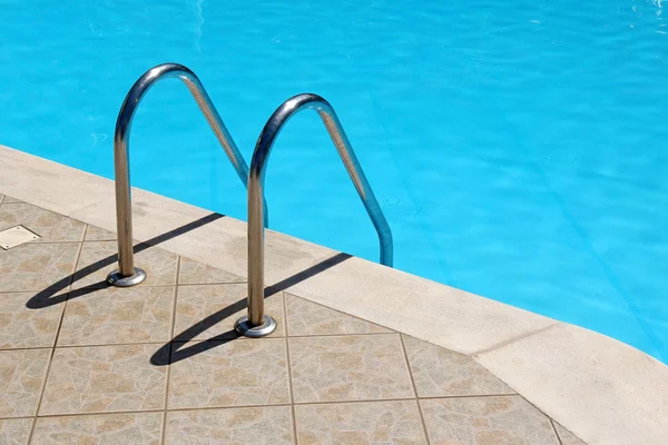 Railing stairs in the blue swimming pool — Stock Photo, Image