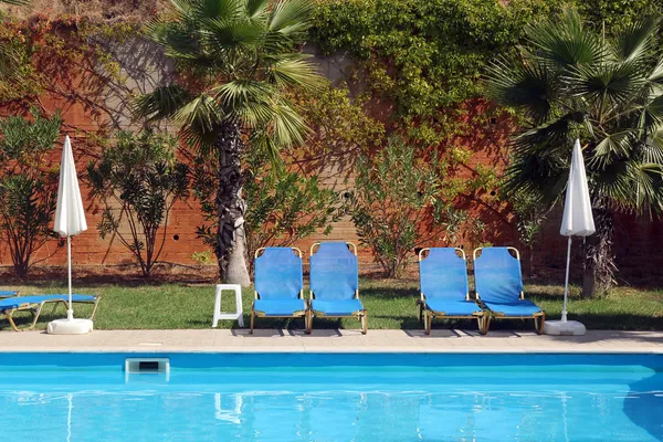 Сонячні ліжка та сонячні парасольки біля басейну — стокове фото