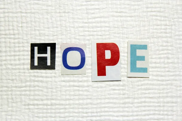 Hope word cut from newspaper on handmade paper background — Stock Photo, Image