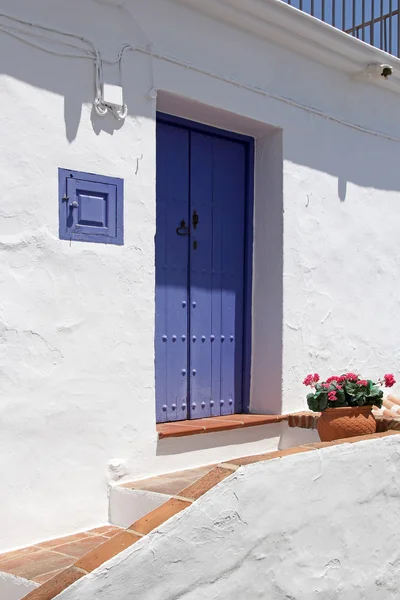 Front side of typical spanish house with blue wooden door