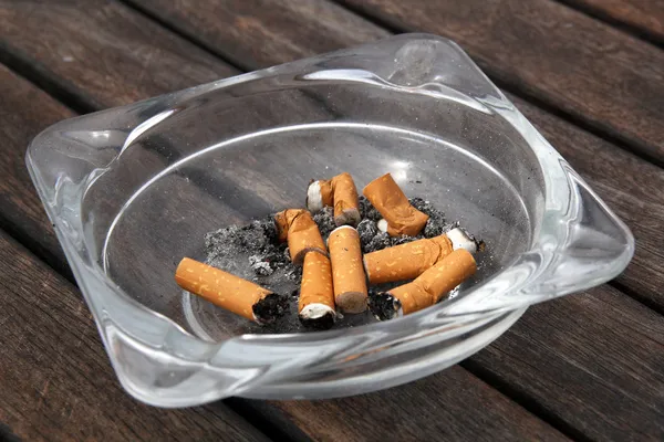 Asbak en sigaretten op houten achtergrond — Stockfoto