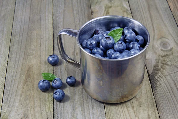 Blueberries in metal cup on wooden background — Stock Photo, Image